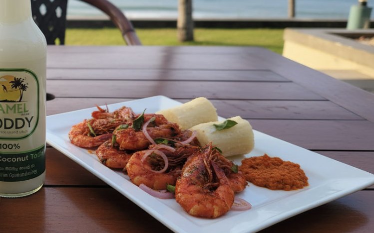 Devilled prawns with manioc and pol sambol beside a Camel Toddy bottle